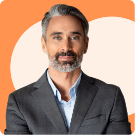 A man with a beard and gray hair is wearing a suit and standing against an orange background.