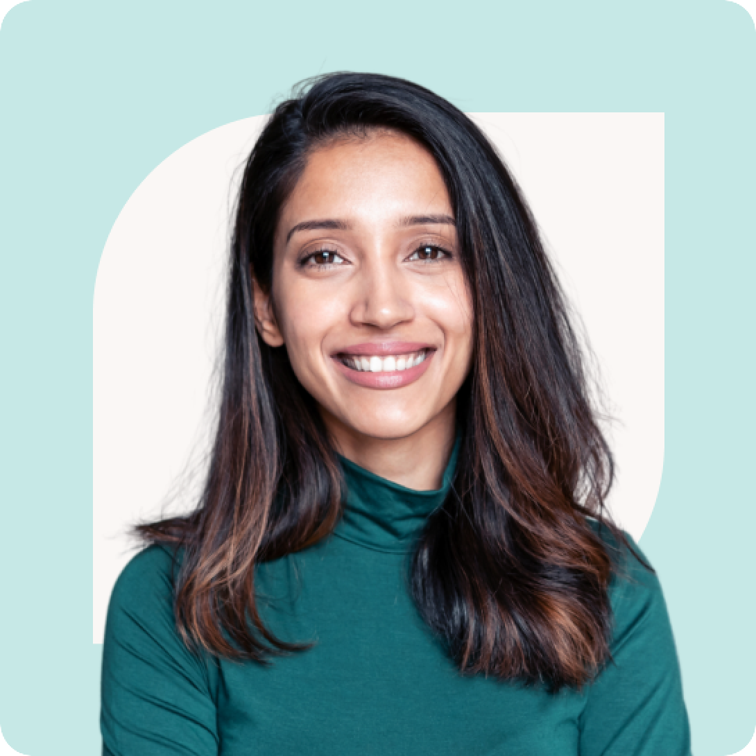 A person with long dark hair wearing a green top smiles against a light blue background.